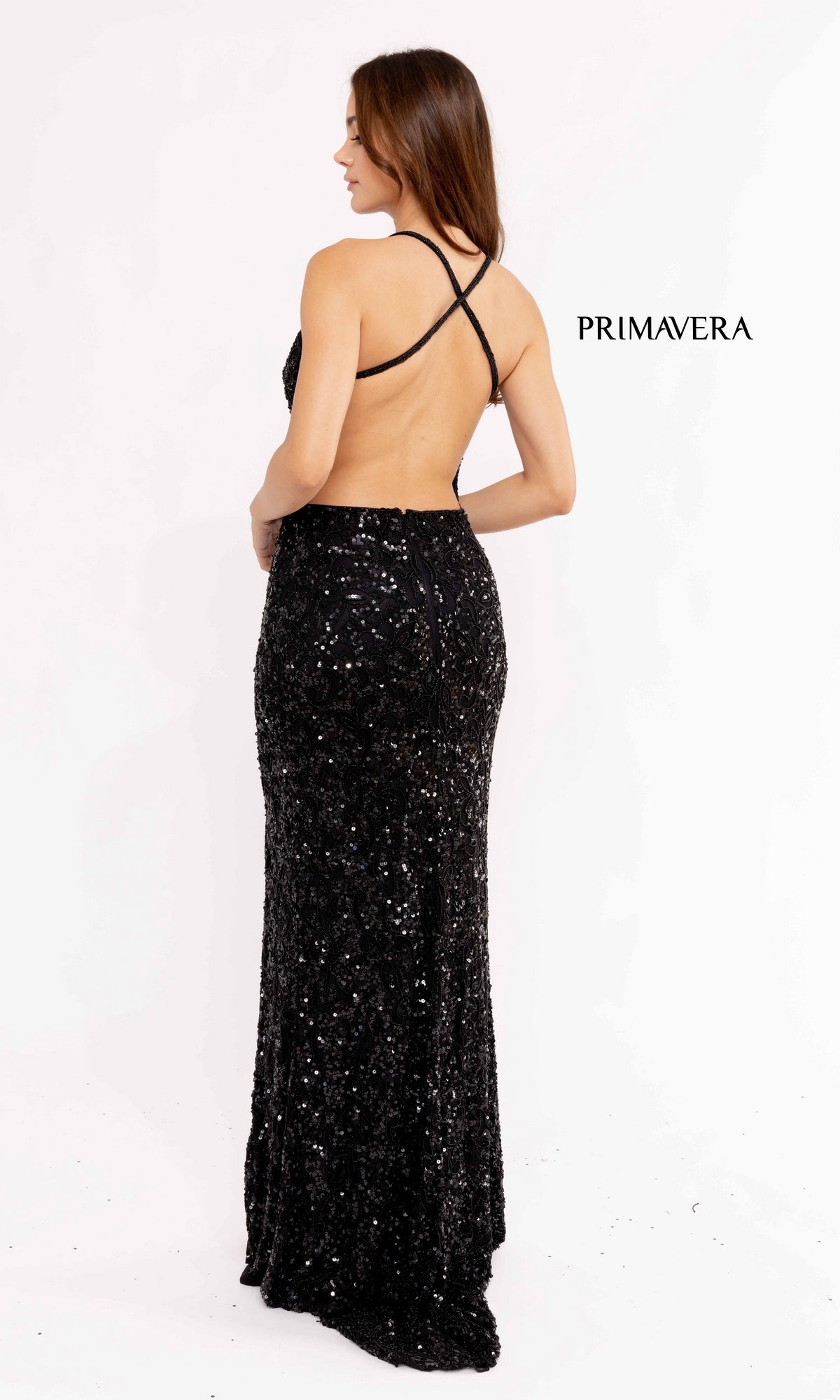 A woman faces away in the Dark Sequin-Pattern Long Prom Dress 3295D, a black, floor-length gown featuring a low back with crisscross straps;